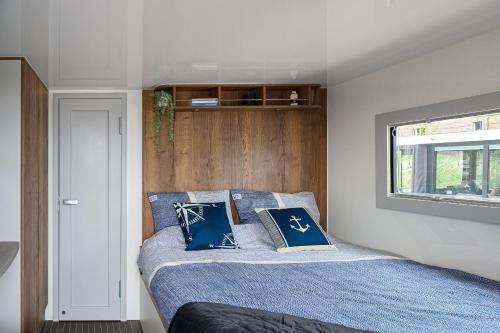 a bedroom with a bed with blue sheets and a window at Tiny Olav houseboat close to the beach and restaurants by Weltevreden Experience in Zeewolde