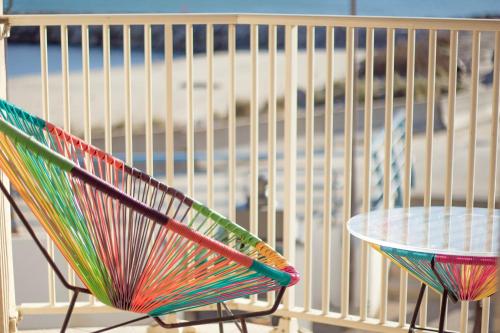 a colorful chair and a table in front of a beach at Hotel Camille in Saintes-Maries-de-la-Mer