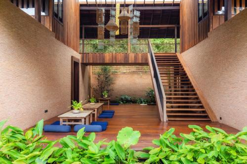 a staircase in a building with plants in the foreground at Athita The Hidden Court Chiang Saen Boutique Hotel in Chiang Rai