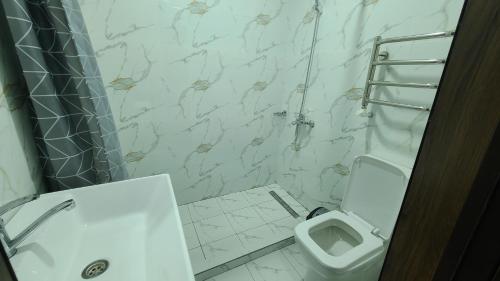 a white bathroom with a toilet and a shower at Volidam Hotel in Karmana