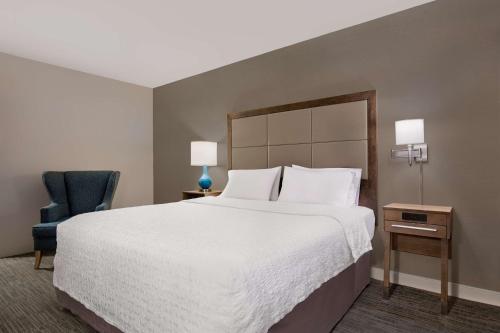 a bedroom with a large bed and a blue chair at Hampton Inn Long Island-Brookhaven in Farmingville