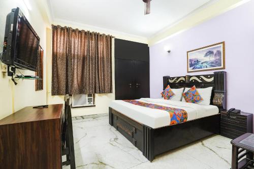 a bedroom with a bed and a desk and a television at FabExpress IVY Inn Sector 35 in Noida