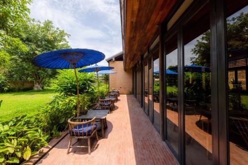 a patio with tables and chairs with umbrellas at Athita The Hidden Court Chiang Saen Boutique Hotel in Chiang Rai