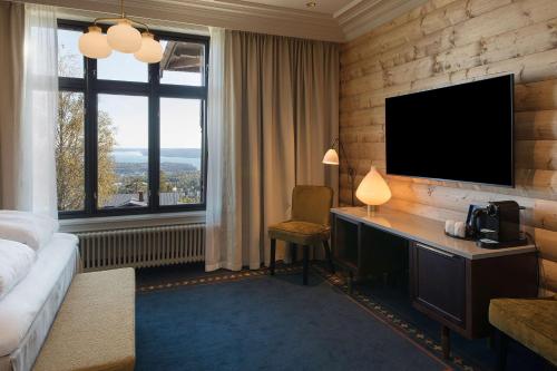 um quarto de hotel com uma secretária e uma televisão em Scandic Holmenkollen Park em Oslo