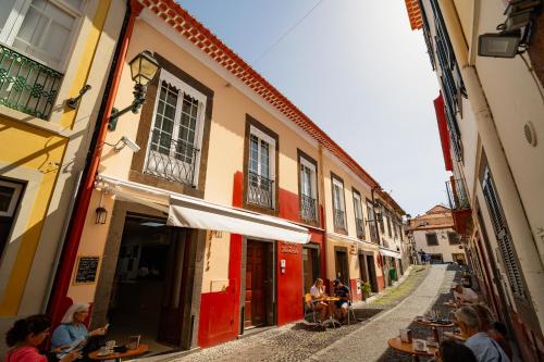 a group of people sitting at tables in an alley at O Cantinho da Mariazinha by Amazing Madeira in Funchal