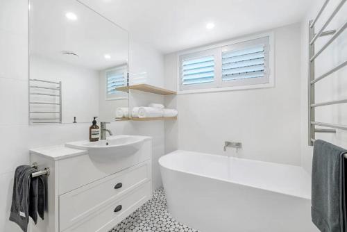 a white bathroom with a tub and a sink at Budds Villa 2 By Khove in Gold Coast