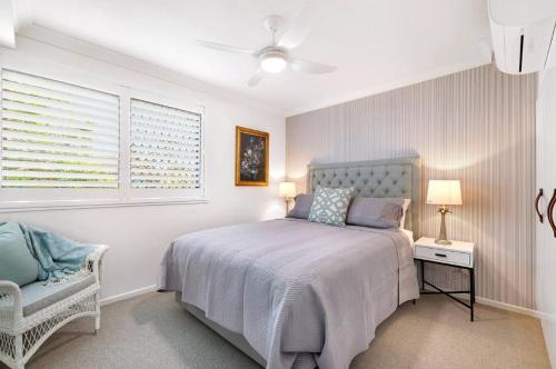 a white bedroom with a bed and a chair at Budds Villa 2 By Khove in Gold Coast