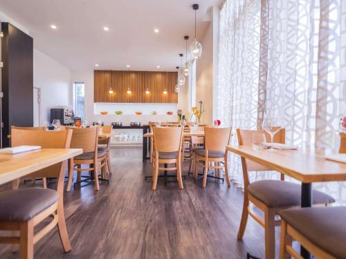 a dining room with wooden tables and chairs at The Sebel Auckland Manukau in Auckland