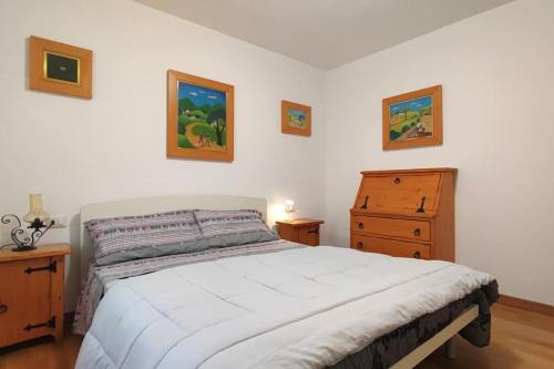 um quarto com uma cama branca e uma cómoda em Casa Vacanza Presolana con giardino e box auto em Castione della Presolana