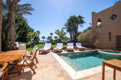 un patio con mesa, sillas y piscina en Beautiful villa at Four Seasons en Sharm El Sheikh