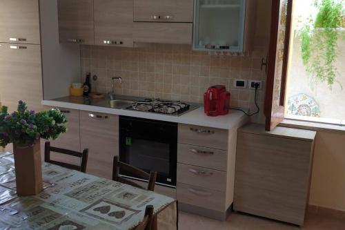 eine Küche mit einem Herd, einer Spüle und einem Tisch in der Unterkunft Borgo San Giorgio Apartment in Castelmola