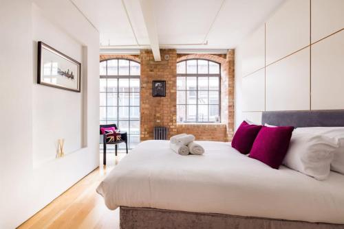 a bedroom with a large white bed with red pillows at Central Soho Loft with A C & Concierge in London
