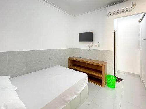 a white bedroom with a bed and a tv at RedDoorz at Kedawung Cirebon 