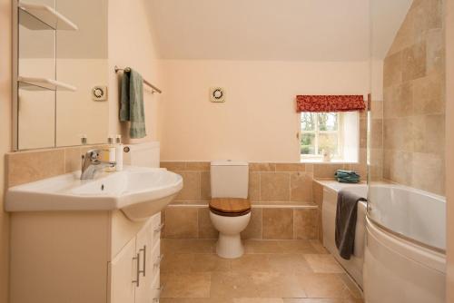 łazienka z umywalką, toaletą i wanną w obiekcie Dairy Cottage w mieście Knapton