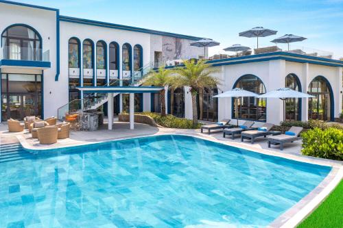una piscina en un hotel con sillas y sombrillas en Wyndham Hoi An Royal Beachfront Resort & Villas en Hoi An
