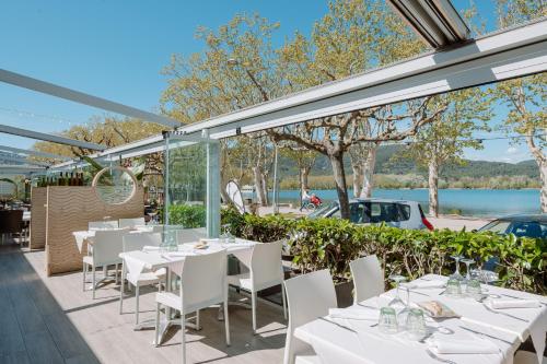 a restaurant with white tables and chairs and a view of a lake at APARTAMENTS LA CARPA in Banyoles