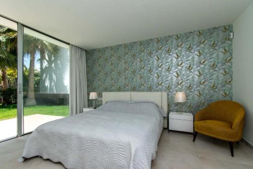ein Schlafzimmer mit einem Bett und einem Stuhl in der Unterkunft Villa Josefa with private heated pool and lake views in Guía de Isora