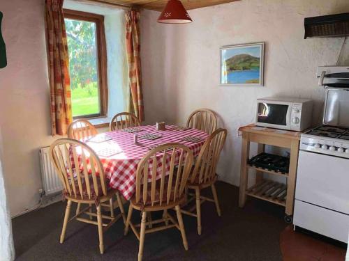 een keuken met een tafel met stoelen en een magnetron bij Deerpark Holiday cottages Dairy in Killaloe