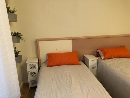 two beds with orange pillows in a small room at Apartamento San Gregorio in Pamplona