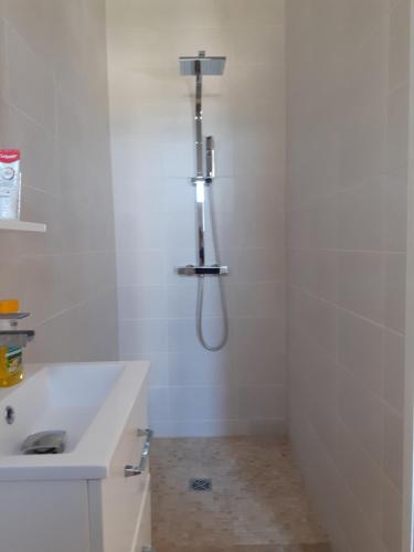 La salle de bains blanche est pourvue d'une douche et d'un lavabo. dans l'établissement Le Gîte du Petit Chenac, à Chenac Saint Seurin D'uzet