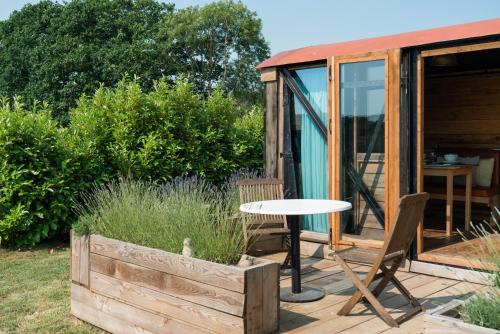 a table and chairs on a deck next to a cabin at Swallowfield Glamping-Station Master in Yeovil