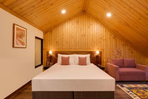 a bedroom with a large bed and a chair at Lemon Tree Hotel, Kasauli in Kasauli