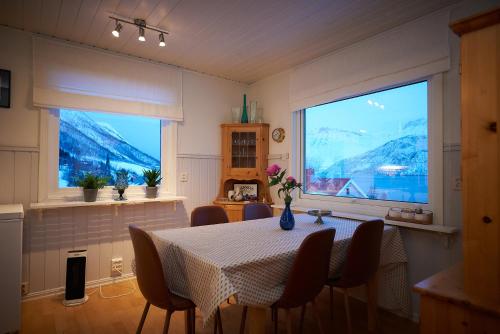 a dining room with a table and two windows at Rigmorhuset in Fjordgård