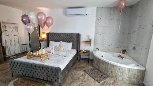 1 dormitorio con bañera, cama y globos en bali carmel zimmer & spa en Dāliyat el Karmil
