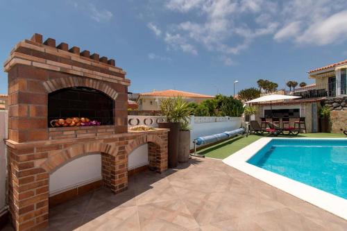 a brick fireplace next to a swimming pool at Villa Clariana in Callao Salvaje