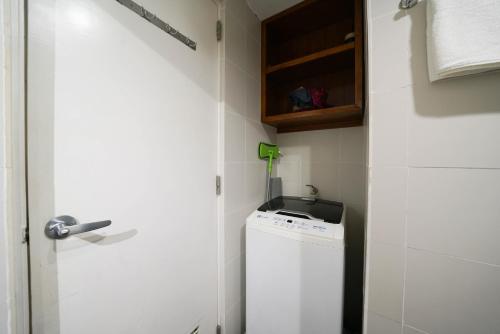 a small bathroom with a washing machine and a door at KL Tower Makati Apartments by PH Staycation in Manila