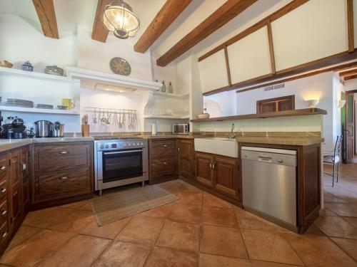 a large kitchen with wooden cabinets and stainless steel appliances at Villa Picassa with sea view in Deia