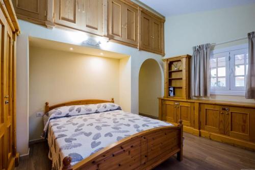 1 dormitorio con cama, armarios de madera y ventana en Villa Freesia with heated pool and air conditionin en San Miguel de Abona