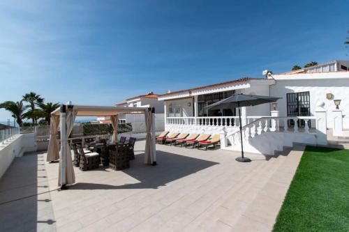 a patio with chairs and umbrellas on a house at Villa Melua in Chayofa