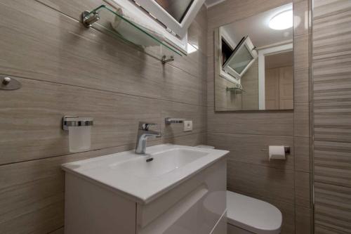 een badkamer met een wastafel, een spiegel en een toilet bij Parque Santiago II 147 - Two Bed in Playa de las Americas