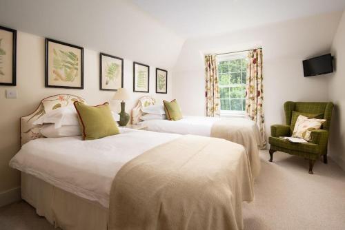 a bedroom with two beds and a chair at Crailing Coach House in Jedburgh