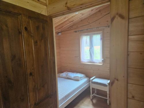 Cette petite chambre comprend un lit et une fenêtre. dans l'établissement Domek letniskowy Zacisze, à Świętne