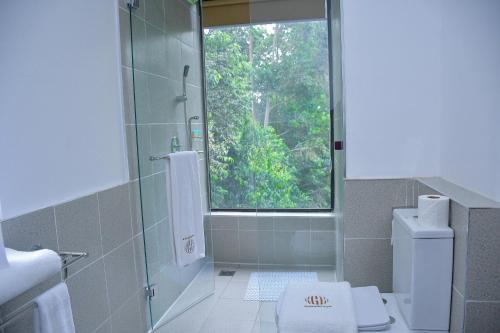 baño con ducha y aseo y ventana en Humphreys HillHouse, en Kisii