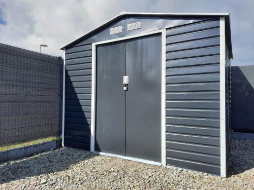 a large metal garage with a gray door on a building at Chabrowa Apartamenty 1 in Milicz