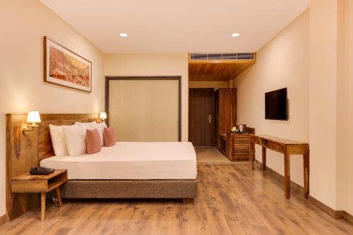 a hotel room with a bed and a tv at Lemon Tree Hotel, Kasauli in Kasauli