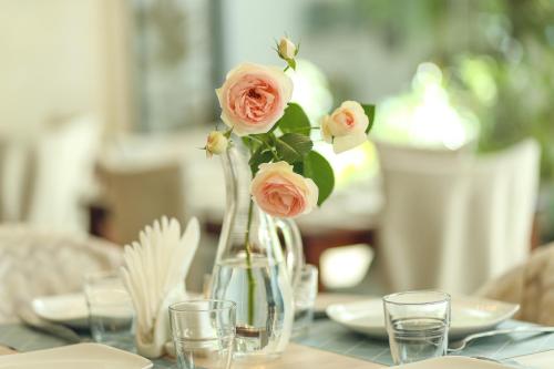 a vase filled with pink roses sitting on a table at Kenari Hotel in Tbilisi City