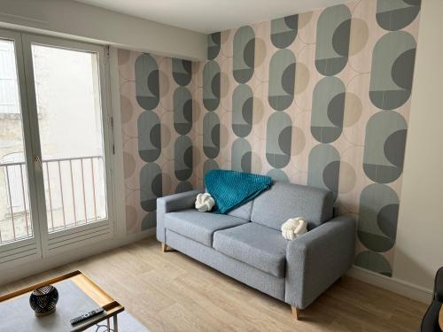 a living room with a gray couch and a wall with geometric wallpaper at Le Cocon central - Wifi - Transports et Commerces in Angoulême