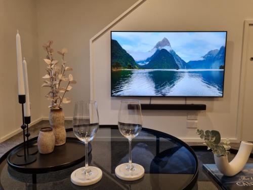 a living room with two wine glasses and a tv at Cloud Nine Elegant Escape Awaits in Christchurch