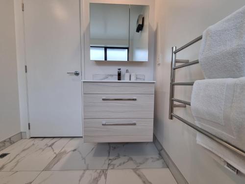 a bathroom with a sink and a mirror at Cloud Nine Elegant Escape Awaits in Christchurch