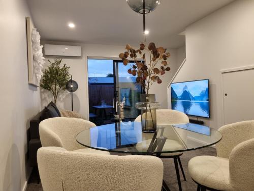 a living room with a glass table and chairs at Cloud Nine Elegant Escape Awaits in Christchurch