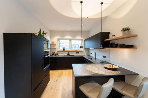 a kitchen with black cabinets and a counter with chairs at See und Sporthotel Ankum mit Lakeside Apartments in Ankum