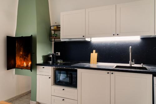 La cuisine est équipée de placards blancs, d'un évier et d'une cuisinière. dans l'établissement Andromeda Luxury Flat, à Modugno