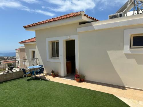 Cette maison blanche dispose d'un balcon avec une table et des chaises. dans l'établissement Apartament na Cyprze, à Peyia