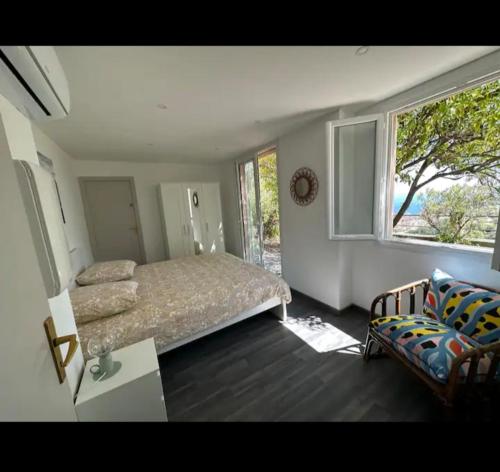 une chambre avec un lit, un canapé et une fenêtre dans l'établissement 10 min de Monaco petite maison avec jardin vue mer et rocher de Monaco, à La Turbie