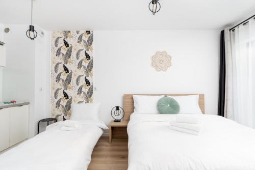 2 camas en un dormitorio con paredes blancas en Chopina Deluxe Studio en Cracovia