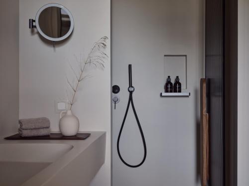 a bathroom with a shower with a sink and a mirror at Stamna Sifnos a member of Design Hotels in Sifnos